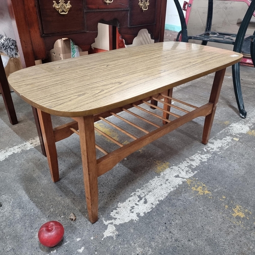 572 - A mid century  coffee table with wood effect top, slatted lower tier for storage and tapered legs.