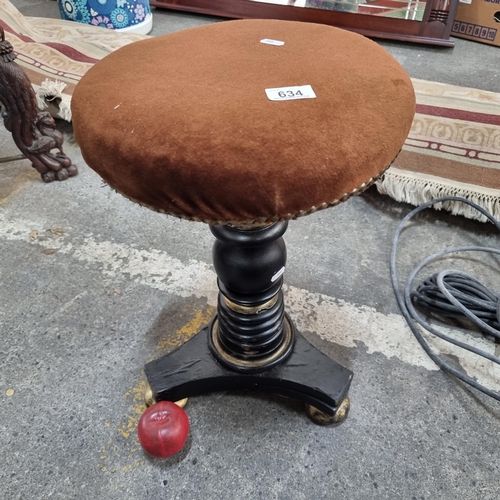 634 - A Victorian mahogany piano stool with turned stem and tripod base with gilt detail. Featuring swivel... 