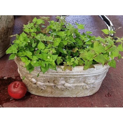 665 - A  heavy reconstituted stone trough planter boasting a high relief floral design.