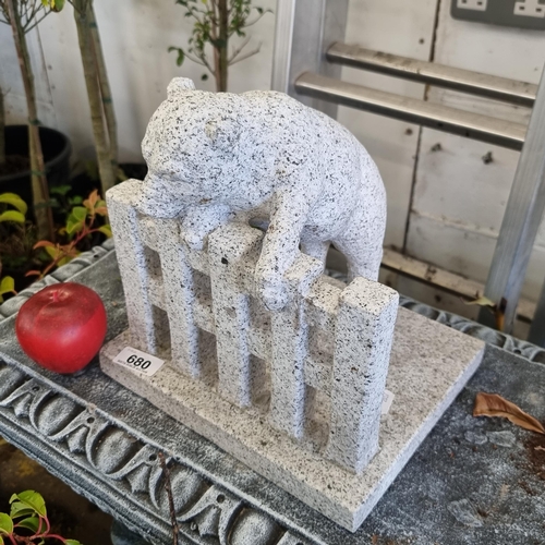 680 - A heavy granite garden figure depicting a pig climbing over a fence. H26cm.