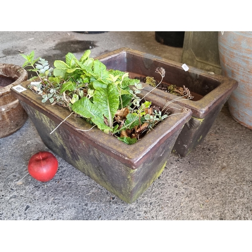 687 - A pair of heavy glazed stone trough planters in a dark brown finish. H20cm x L42cm x W21cm.