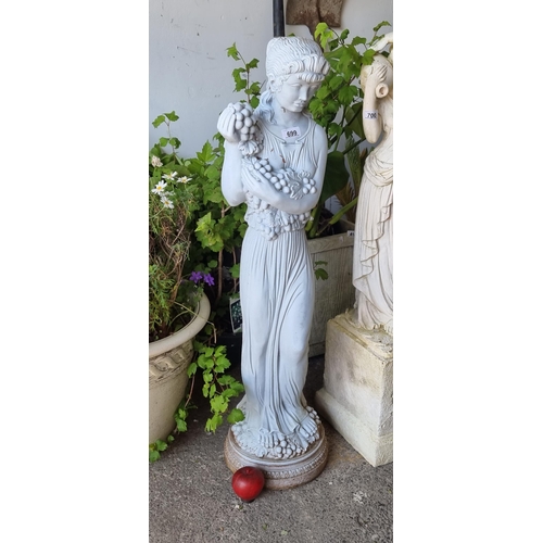 699 - A striking plaster garden figure of an elegant woman holding a bunch of grapes. Held on a round pede... 