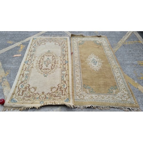 240 - Two neatly sized hall runner rugs in shades of beige, sand, pink and green. 
MM: 197 x 91 cm each