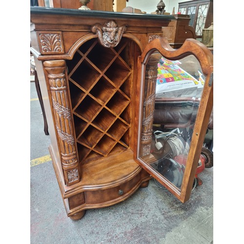 433 - Star Lot - An ornate wine cabinet to store ten bottles. Sporting billy goat mask detail flanked by r... 