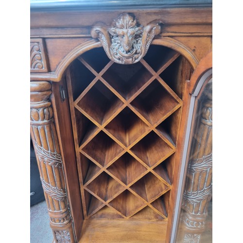 433 - Star Lot - An ornate wine cabinet to store ten bottles. Sporting billy goat mask detail flanked by r... 