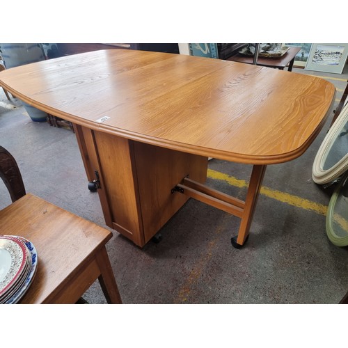 452 - A fantastic gate leg mid century drop leaf table with two legs that fold out to each side, flanking ... 