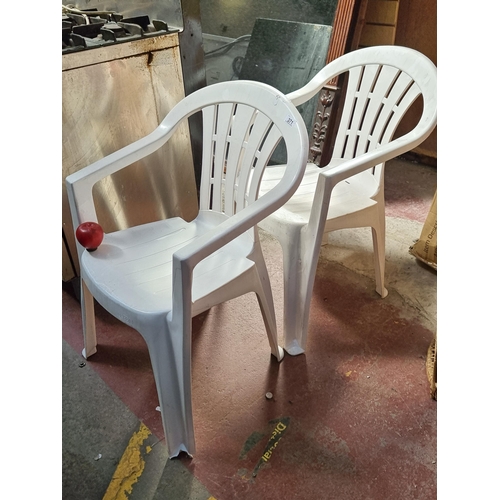 371 - A pair of white plastic garden chairs from Jardin with pierced backrests and comfortable armrests. S... 