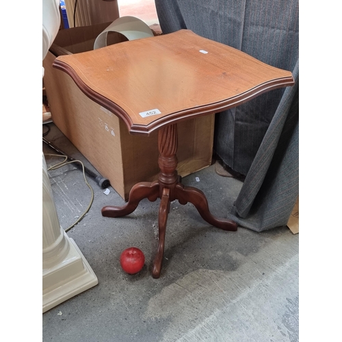 452 - A charming wine table with a serpentine edge, string inlay and held on quadruplet cabriole feet.