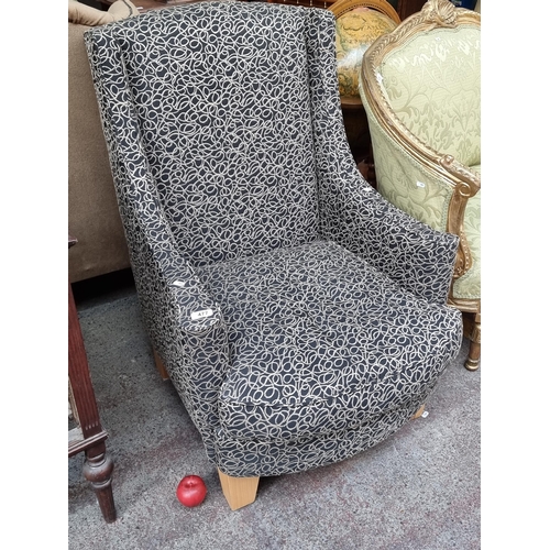 477 - A very nice high backed armchair. Upholstered in a black upholstery with gold spiral and curvilinear... 