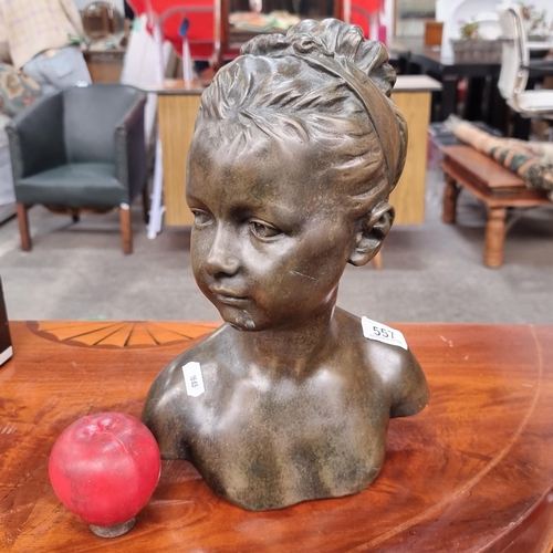 557 - A bronze toned sculptural bust of a young girl with her hair held up in a ribbon