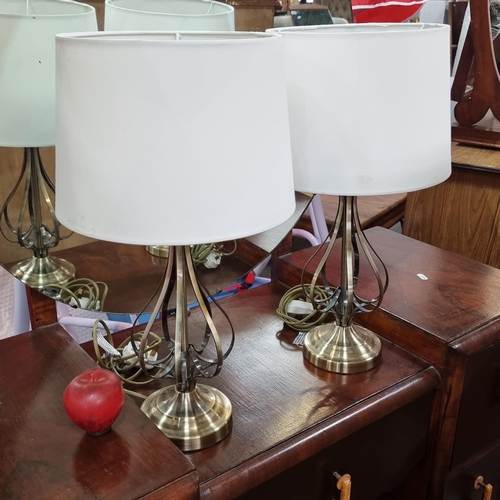 771 - Two table lamps with curved openwork metal bases and topped with light cream shades.