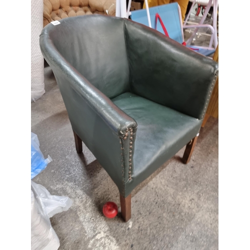 670 - A vintage tub chair upholstered in a dark green leather with stud detail on a wooden frame.