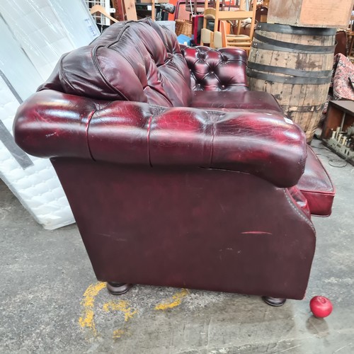 812 - A fabulous Chesterfield three seater couch in an ox blood red leather with button back cushions. In ... 