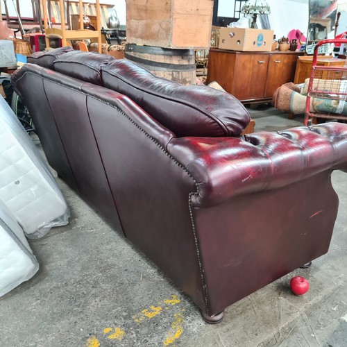 812 - A fabulous Chesterfield three seater couch in an ox blood red leather with button back cushions. In ... 