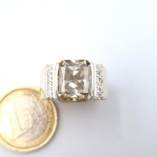 24 - A very unusual cushion cut Moissanite stone ring, set with a thick banded intricately finished mount... 