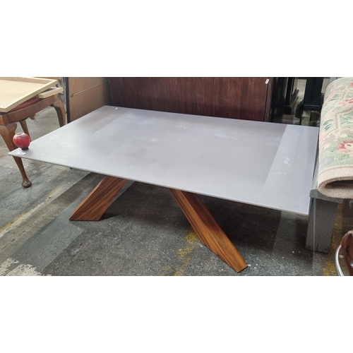 711 - A large modern coffee table with a frosted glass top in a purple shade held on angular solid wood le... 