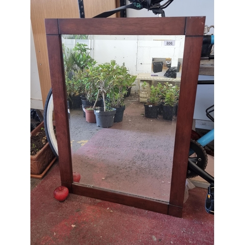 806 - A large contemporary bevelled wall mirror with sleek rectangular wooden frame.