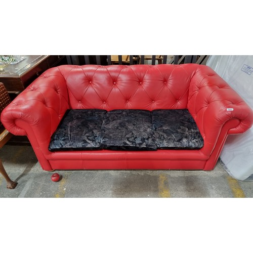 721 - Star Lot : A striking Chesterfield style sofa upholstered in a red button back leather with a trio o... 