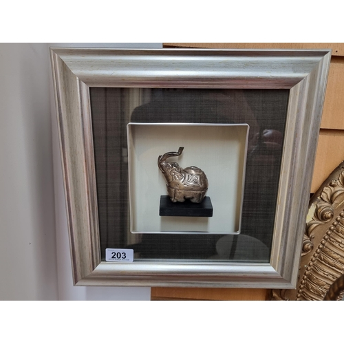 An unusual framed Elephant figure. A silver toned Indian example housed in a distressed silver frame with dark grey matting.