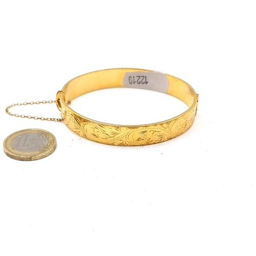 36 - A 22 carat vintage 1960s gold plated (stamped to band) bangle bracelet, set nicely with a foliate mo... 