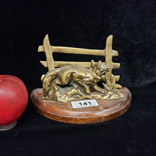 141 - A wonderful vintage bras letter holder depicting a fox walking by a fence. Held on a wooden base.