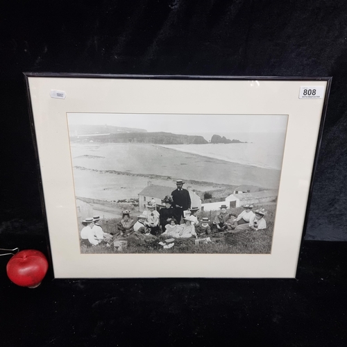 808 - A large high quality photographic print showing a late Victorian family enjoying a picnic by the bea... 