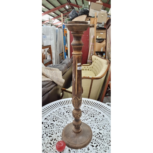 661 - A tall floor standing wooden candle stick holder with lovely carved detail to stem in the form of fl... 