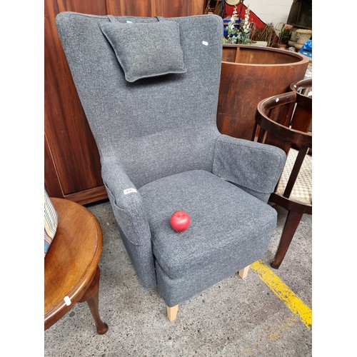 496 - An attractive contemporary wingback armchair. Designed in a slate grey tweed. The model is OMTANKSAM... 