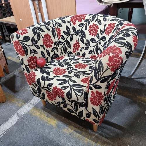 675 - A very comfortable tub chair upholstered in a floral fabric in tones of red and cream. All held on t... 