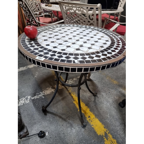 687 - A charming outdoor dining table with a round top boasting a geometric mosaic pattern in black and wh... 