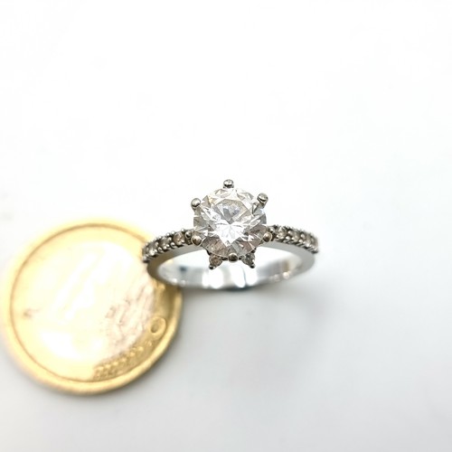 9 - A striking 9 carat White Gold Solitaire ring, set with a central White Sapphire and gem set shoulder... 