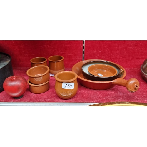 259 - A selection of eight ceramic pieces including terracotta examples such as a pan with a handle and a ... 