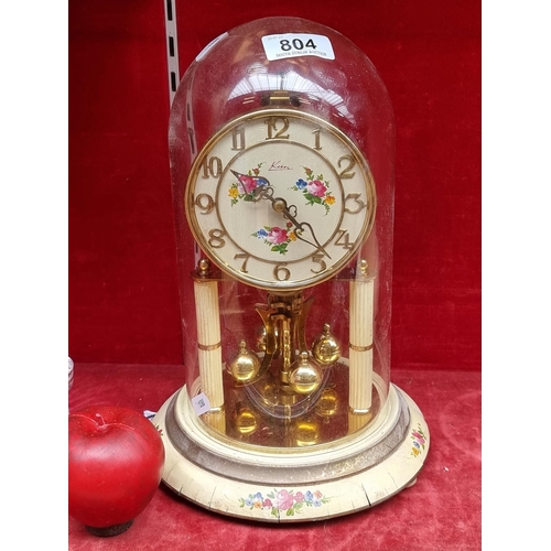 804 - A German made vintage Kern & Sohne dome clock with a rotating pendulum, highly ornate floral motifs,... 