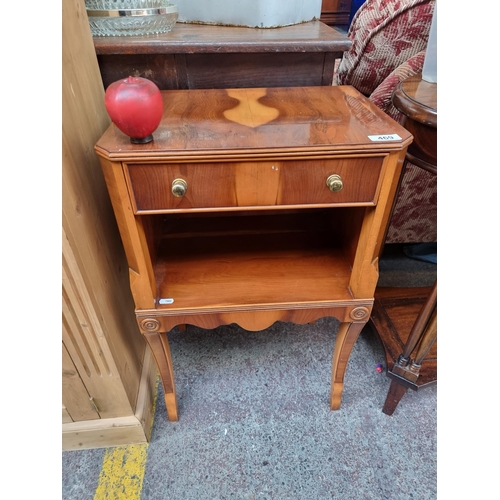 469 - A charming neatly proportioned bedside locker. Designed with a flame wood and a neat drawer with bra... 