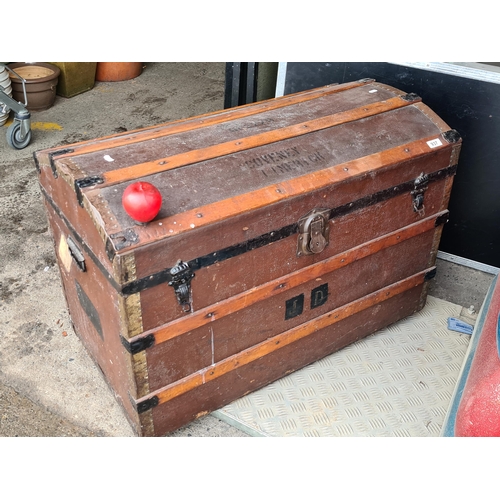 937 - A very large antique wooden domed top travel trunk bound in leather and featuring metal fittings. Wi... 