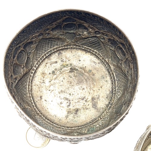 27 - A duo of Chinese  silver antique tea bowls, each featuring worked Repousse motifs which includes rab... 