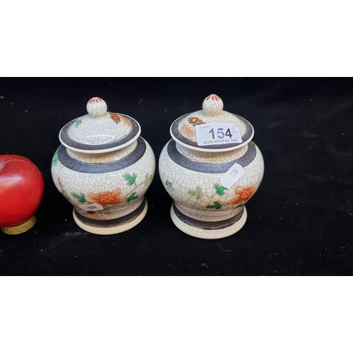 154 - A pair of vintage Chinese lidded pots. Handpainted with floral motifs and phoenix birds. Signed to b... 