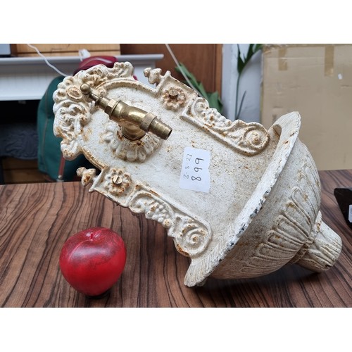 899 - A heavy cast metal garden fountain with a brass tap and ornate foliate decoration. In a cream finish... 