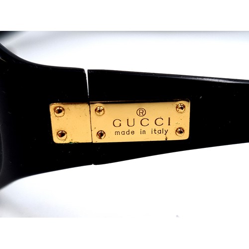 23 - A stylish pair of genuine Gucci wrap around sunglasses, featuring clean unmarked dark lenses and pre... 