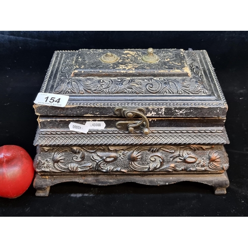 154 - A carved wooden hinged box with an ebonised finish and brass locking mechanism. Containing some mixe... 