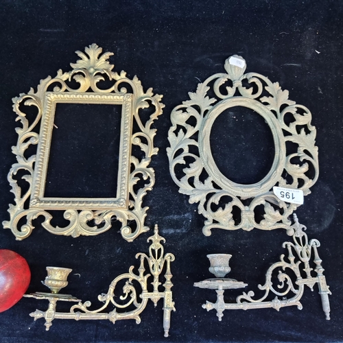 195 - Four heavy brass  objects including two ornate picture frames with a pair of candle scones. All anti... 