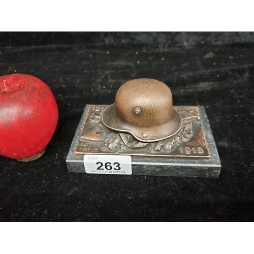 263 - A heavy commemorative World War I item in the form of a military helmet and knife. Held on a granite... 