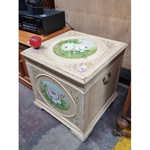 569 - A vintage lidded chest with a handpainted floral motif on a distressed cream ground. With hinged lid... 