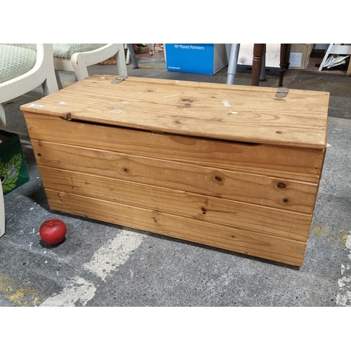 944 - A large wooden pine box with a hinged lid and handle gaps for easy transport. H37cm x L80cm x W39cm