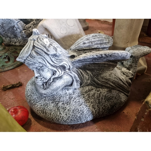 991 - A reconstituted heavy stone garden sculpture of a reclining fairy. Finished in a dark grey wash. L43... 