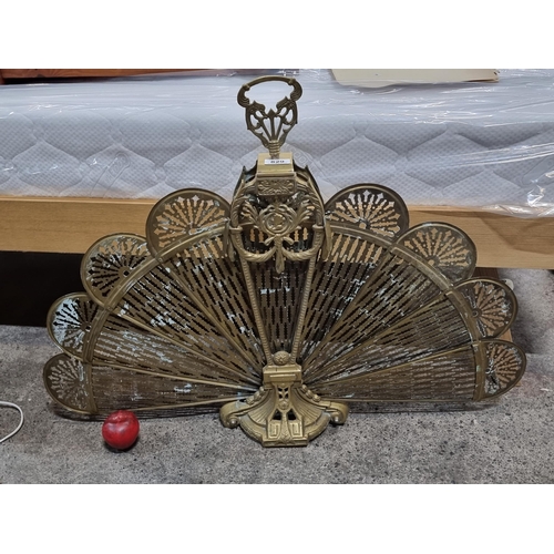 829 - A beautiful pierced brass peacock fire screen. Featuring ornate fans and large handle. in good condi... 