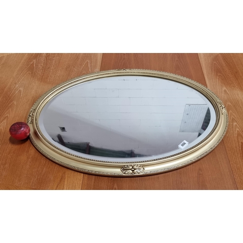 900 - A large handsome oval wall mirror with bevelled glass held in a gilded wooden frame. H60cm x W85cm