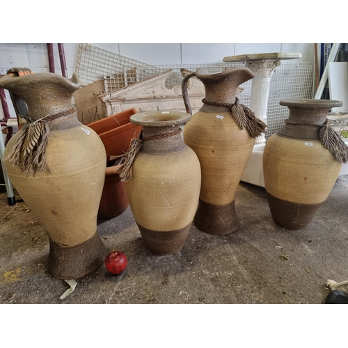 917 - Four large matching terracotta vases including two larger pitcher style examples. In a soft sand and... 