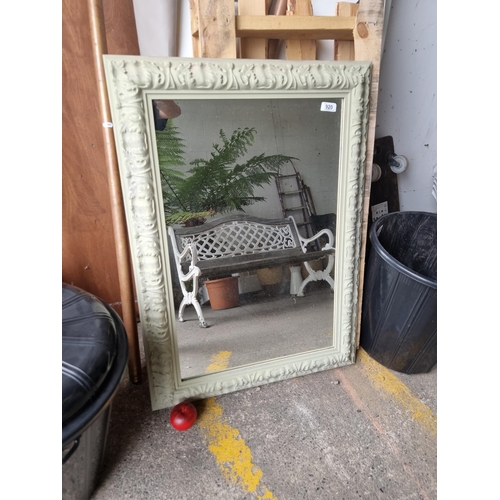 920 - A large wall mirror housed in a charming carved wooden frame in a light grey finish featuring a fleu... 