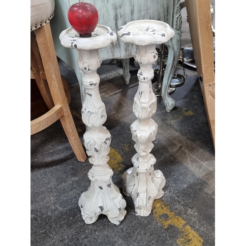 941 - A pair of large cast metal pillar candle holders in a distressed cream finish. H70cm